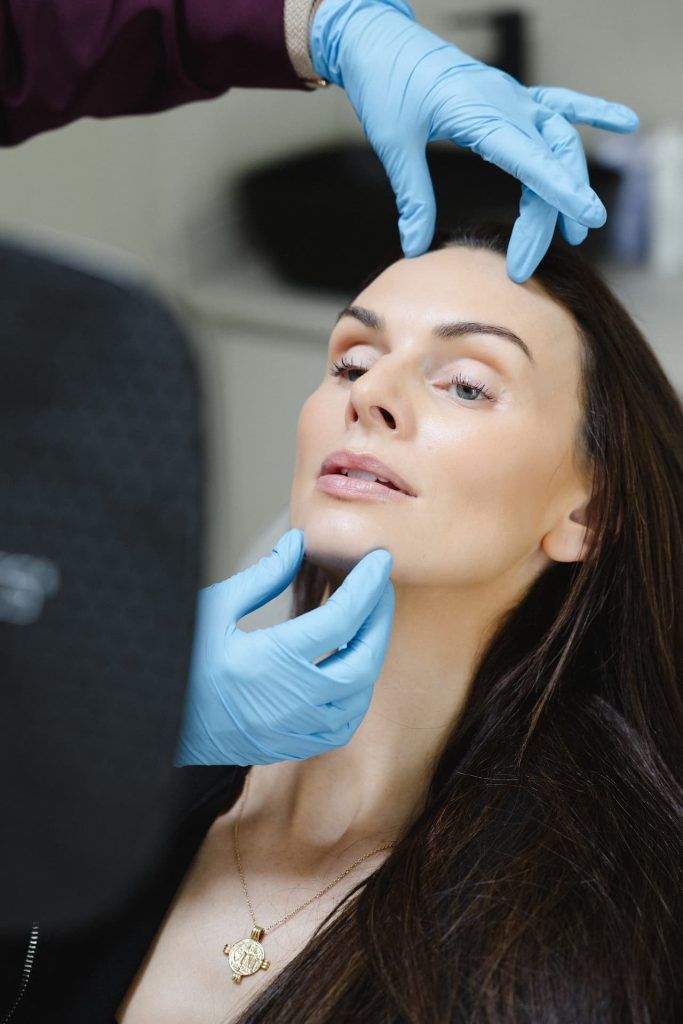 a woman with blue gloves touching her face