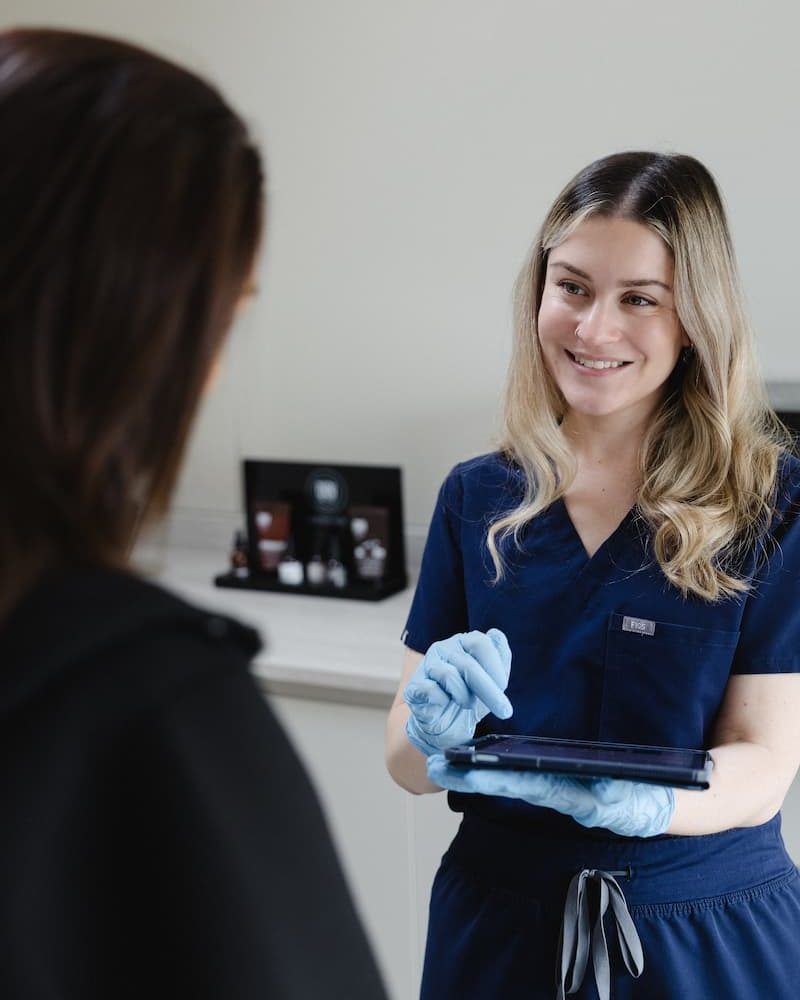 a woman in blue scrubs holding a tablet