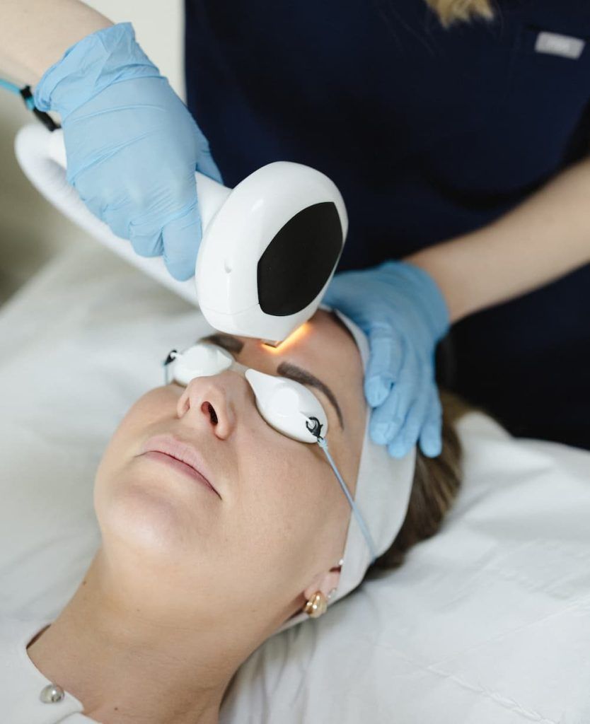 a woman lying on a bed with a laser device
