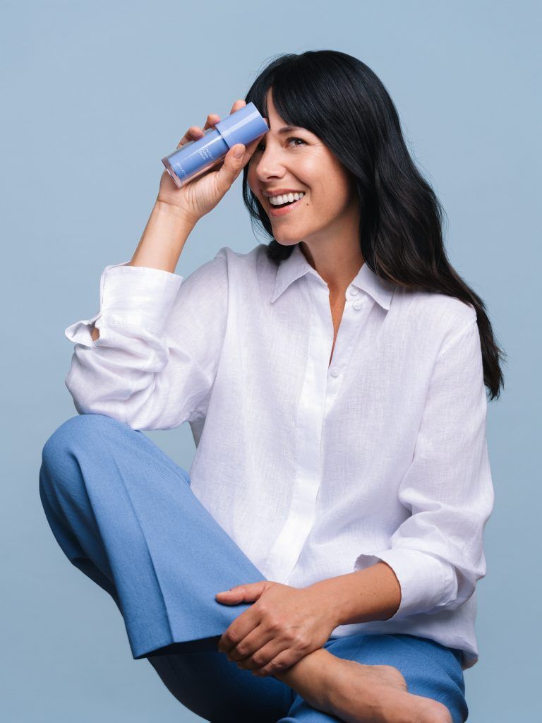 a woman holding a bottle of moisturiser